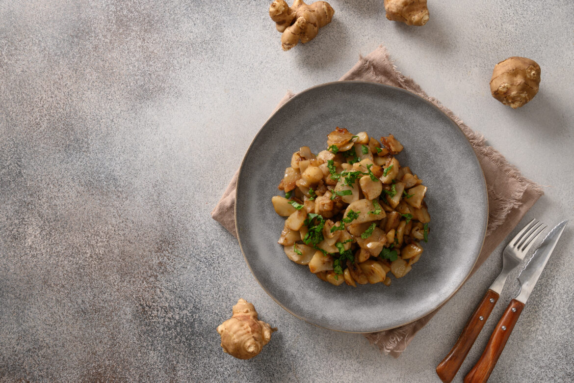 Roasted Jerusalem artichoke root, sunchokes on dark brown.